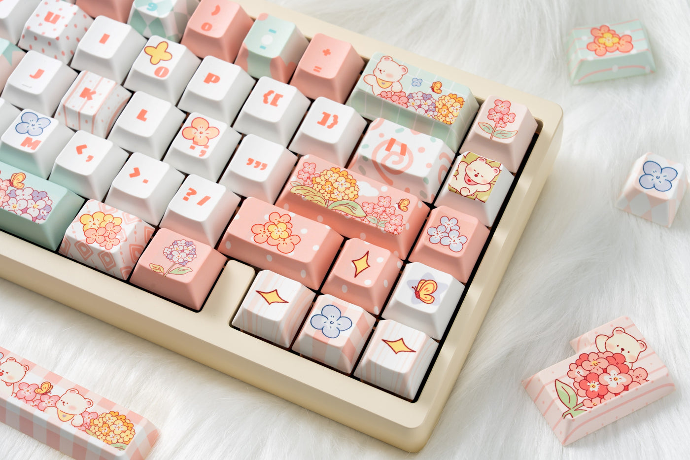 Close-up of Bear Flora pink, mint and white floral keycaps on a cream keyboard.
