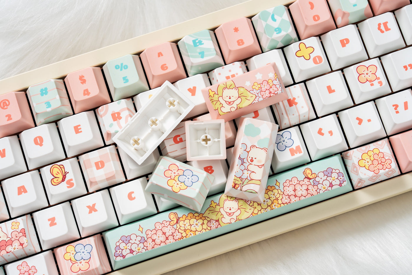 Close-up of Bear Flora floral keycaps and loose keycaps arranged over a cream keyboard.